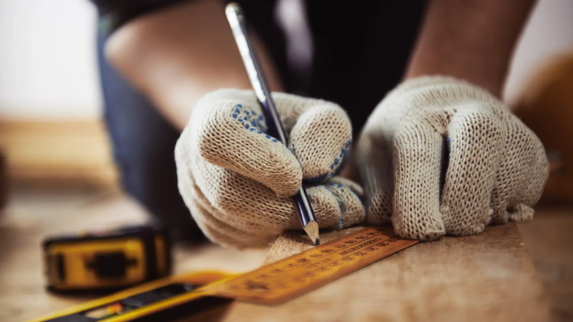 Personne mesurant du bois avec un crayon et une règle